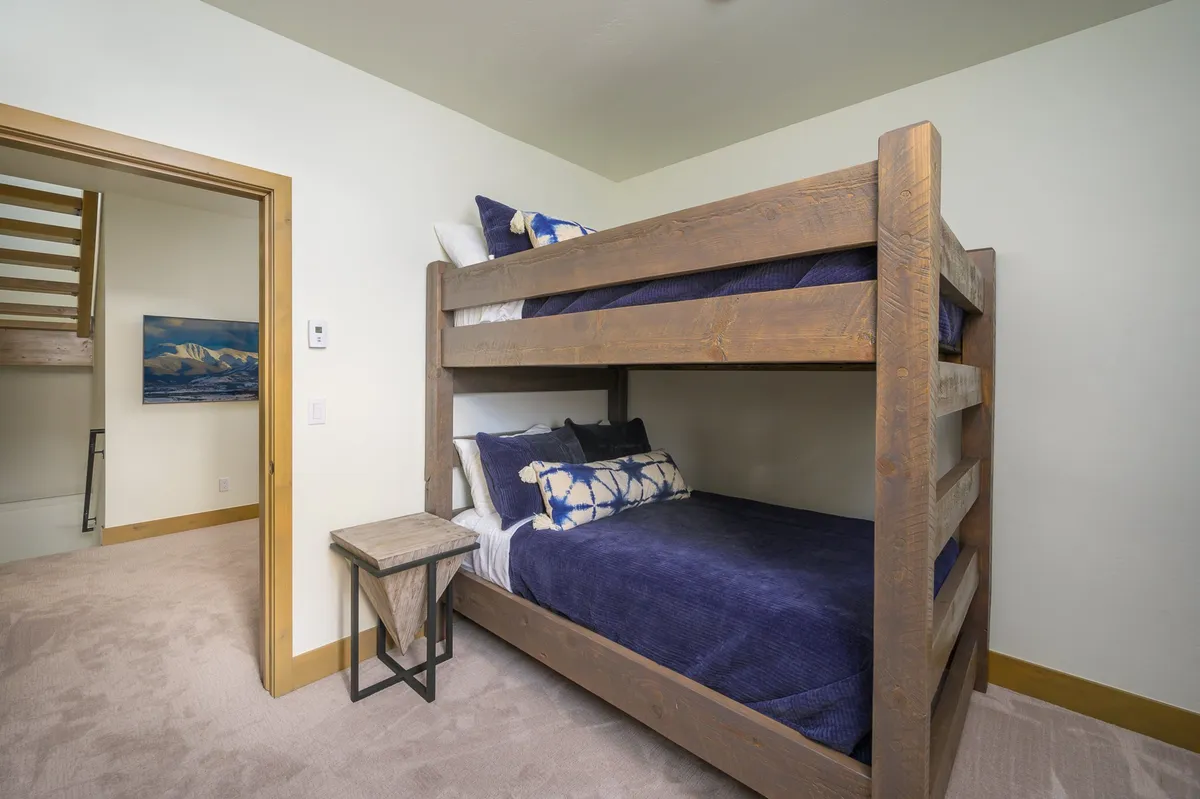 A playful bunk room setting with a sturdy bunk bed, decorative pillows, and a nightstand, evoking a sense of fun and flexibility for kids or group stays.